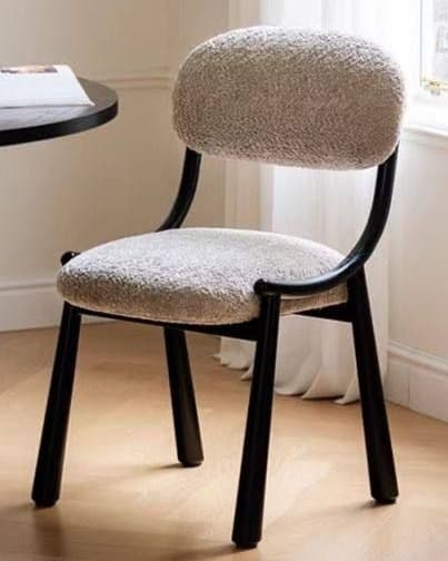 ÉLIA premium upholstered dining chair with rounded cream boucle-style back and seat, curved dark wooden frame and tapered legs.