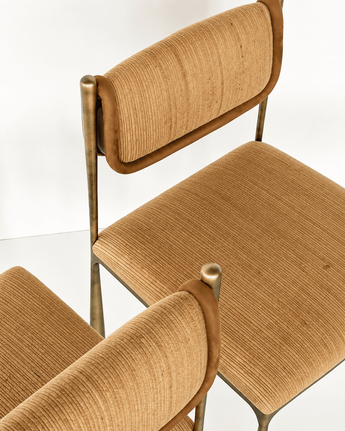 ELVIA upholstered dining chairs with textured tan fabric seats and curved backrests, supported by slim metallic frames.