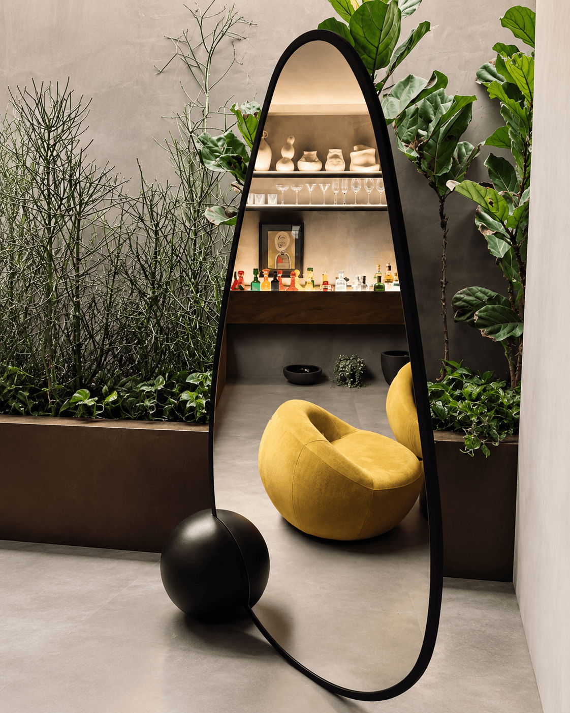 SOMBRA sculptural floor mirror with curved black frame and spherical wooden base in a contemporary interior by rasahaus.