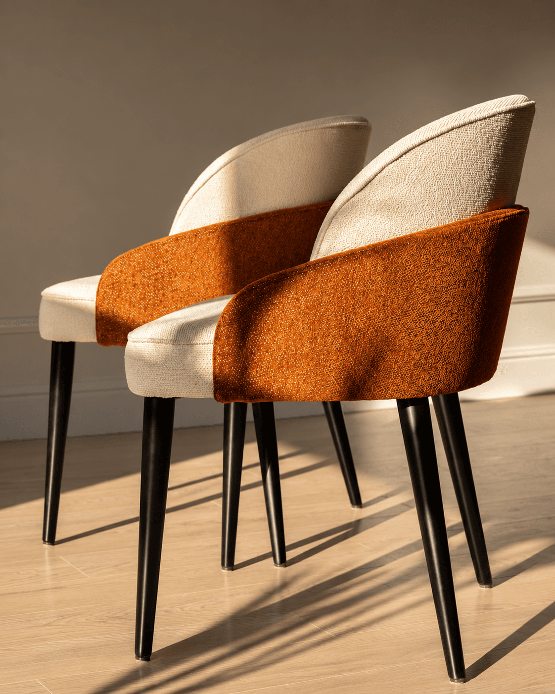 VÉRA dining armchairs with cream and rust-brown textured upholstery and slim black legs in a warm contemporary interior.