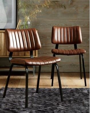 BRUNE channel-tufted dining chair in tan-brown upholstery with a slim black metal frame in a stylish interior.