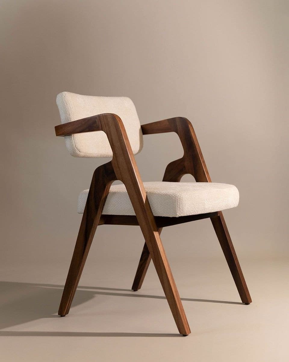ALBA premium dining armchair with curved walnut wooden arms, cream upholstered seat and back, and sculptural wooden frame in an elegant interior.