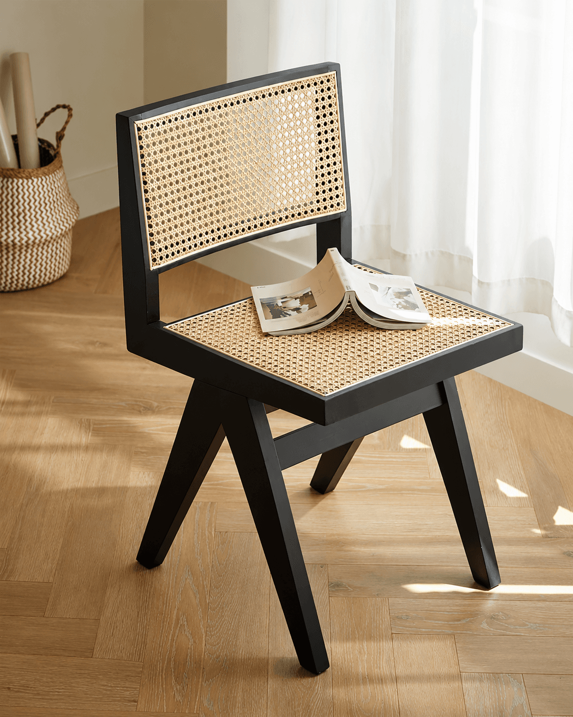 MÉRA modern cane dining chair with black wooden frame and woven cane seat and back in a dining interior.